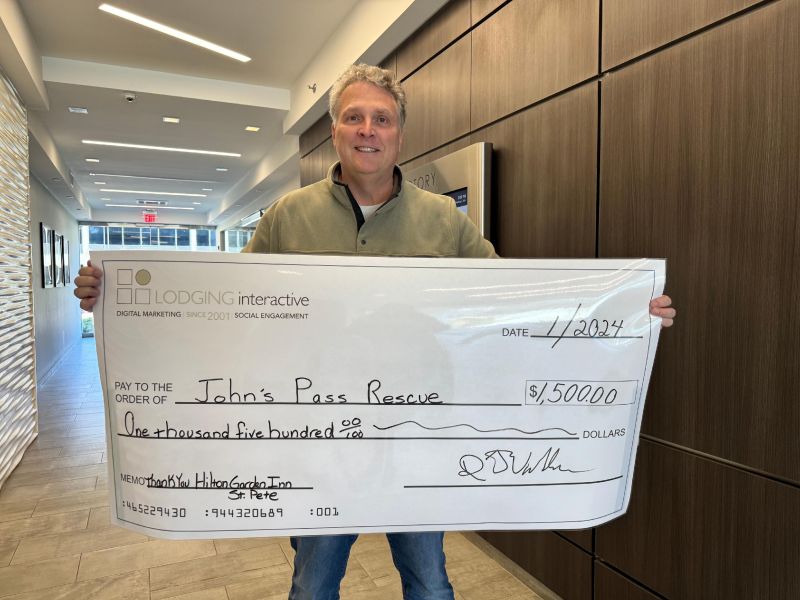 Lodging Interactive’s Founder & CEO holding the ceremonial check paid to John’s Pass Animal rescue on behalf of the Hilton Garden Inn Hotel in St. Pete Beach, FL. — Photo by Lodging Interactive