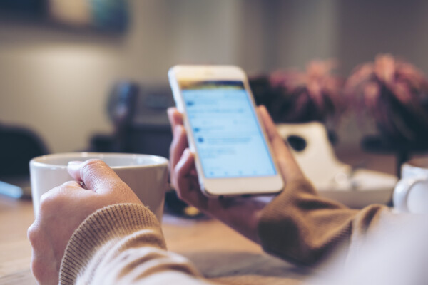 Close-up of a person's hand holding a cellphone, looking at a job advertisement on social media.