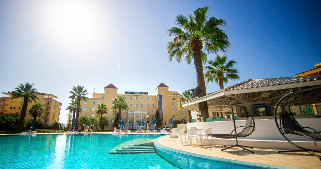 A swimming pool with lounge chairs and palm trees, offering a spectacular pool view at the 5-star Adriatik Hotel in Durres, Albania.