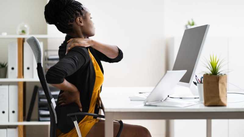 bad posture while working: lady sitting at desk with painful shoulder