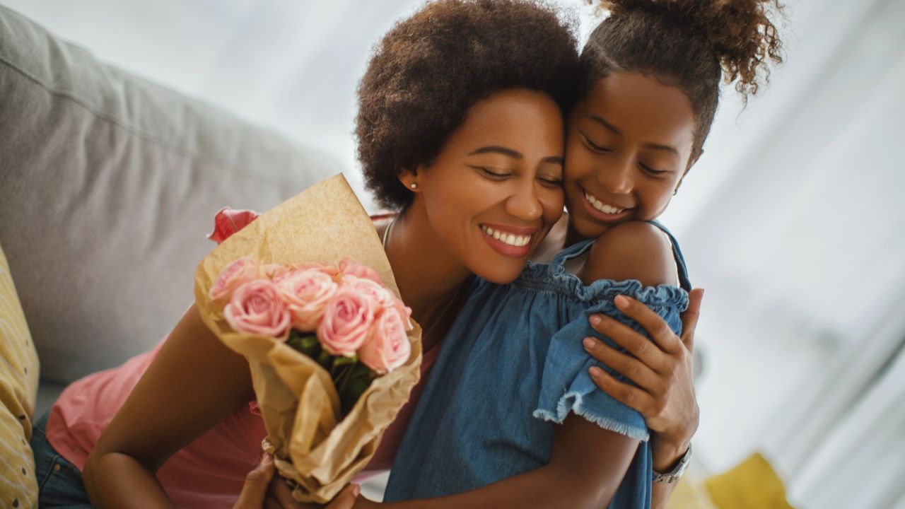 young girl give mother flowers as they embrace