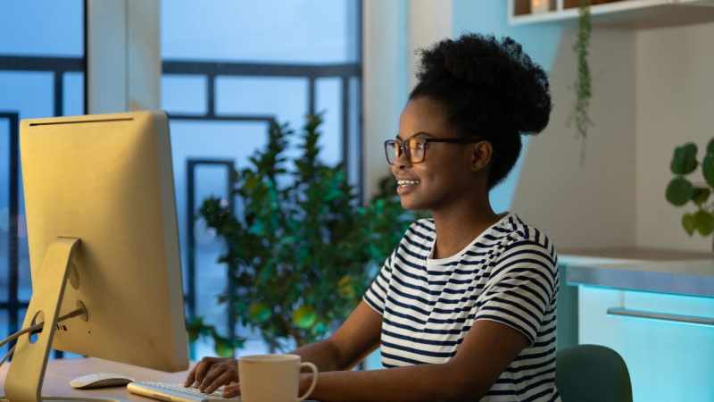 ergonomics for the home office: freelancer in glasses working at her cozy home office desk and drinking coffee 