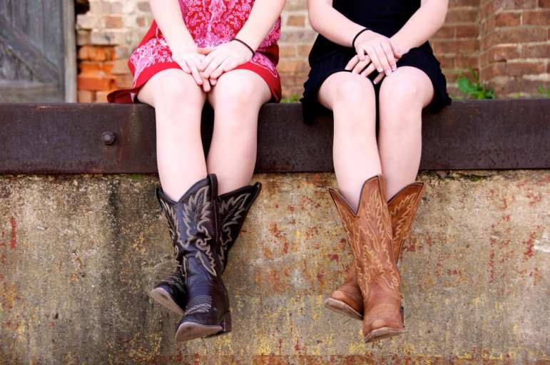 planet cowboy - girls sitting on a wall wearing cowboy boots