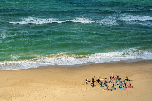 group of people performing yoga on the beach