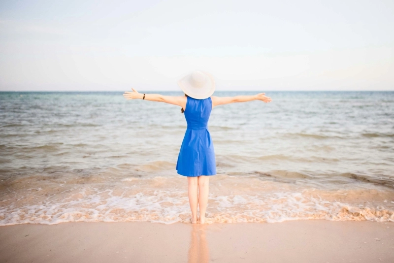 a woman in a blue dress standing on a beach