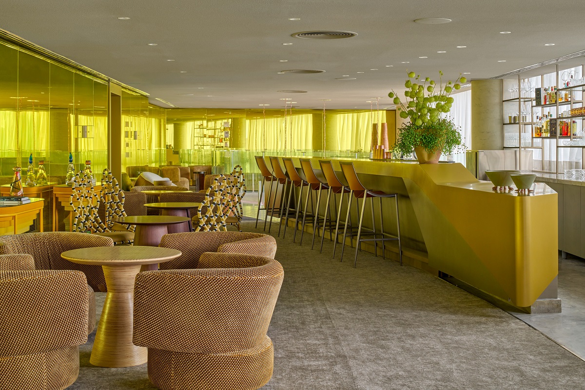 gold and yellow tables and chairs in bar and restaurant with yellow curtains filtering light