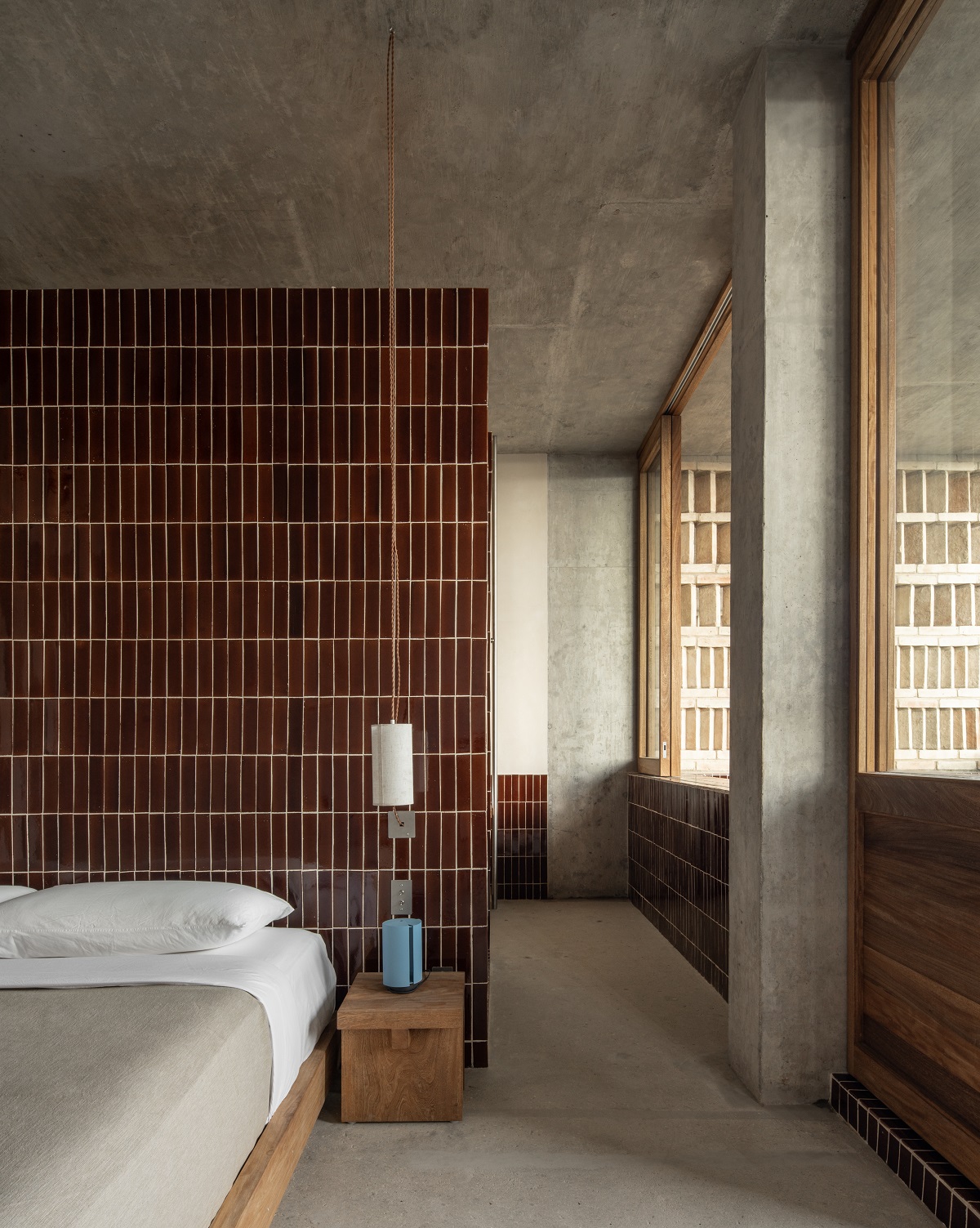 concrete walls and red tiled wall behind the bed