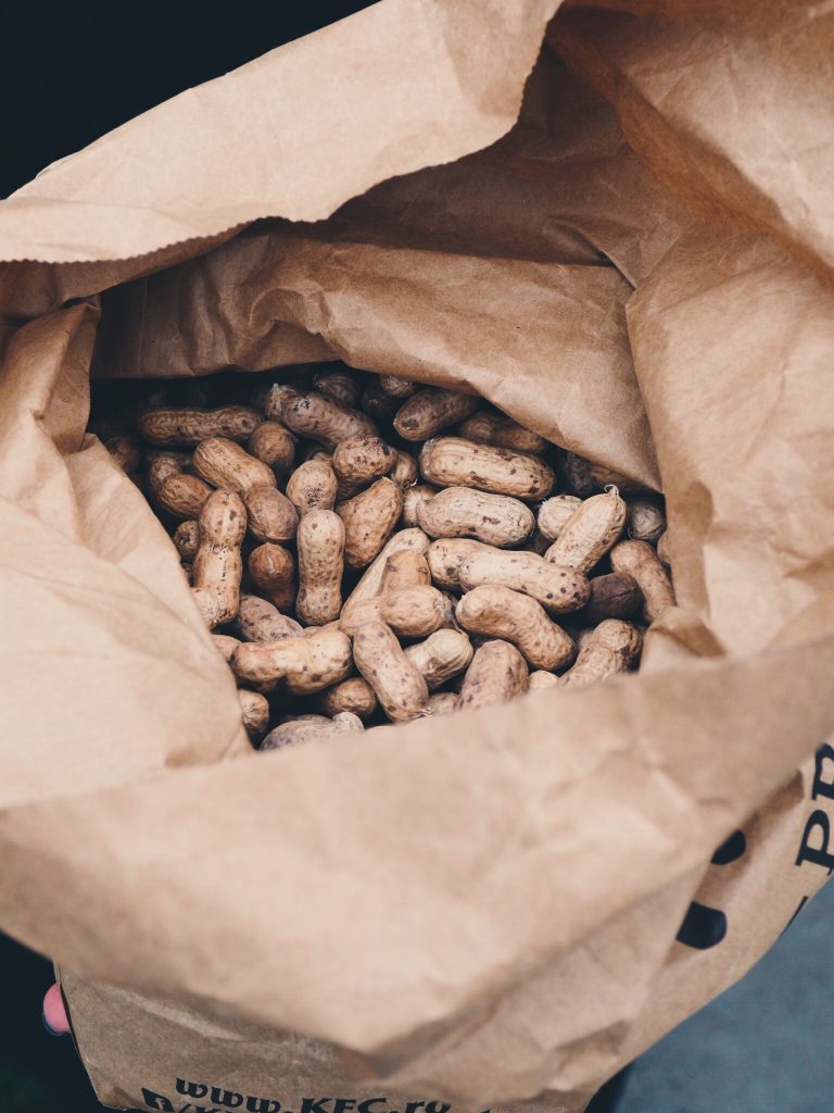 Large amount of peanuts in brown paper bag.